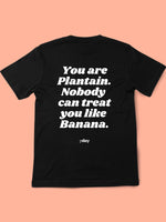 PLANTAIN BLACK BACK Black Y Day Apparel T-shirt with fun foodie slogan on the back: You are plantain. Nobody can treat you like Banana., in white font. It’s celebrates self worthiness. Available to Purchase from Y Day Apparel.com