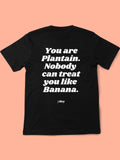 PLANTAIN BLACK BACK Black Y Day Apparel T-shirt with fun foodie slogan on the back: You are plantain. Nobody can treat you like Banana., in white font. It’s celebrates self worthiness. Available to Purchase from Y Day Apparel.com